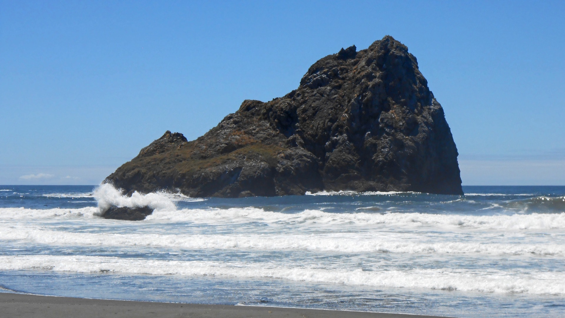 Large coastal rock formation rising from the surf